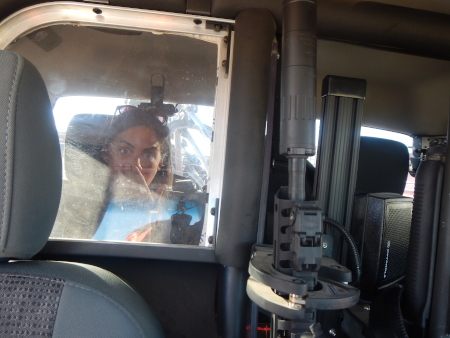 Ruth in the reinforced cell seat in the sheriff's car with his guns in the foreground