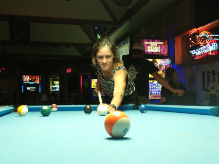 Ruth playing pool in a drunken haze as locals go about their business in the bar