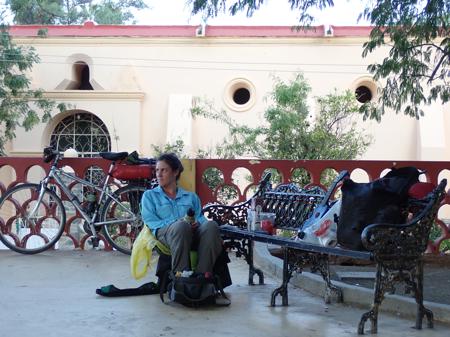 Ruth sitting in the town square of San Antonio by a bench surrounded by panniers and the Ukulele