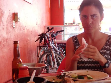 Ruth seeing off her lunch of ceviche in a red painted restaurant and the bikes perched against the wall