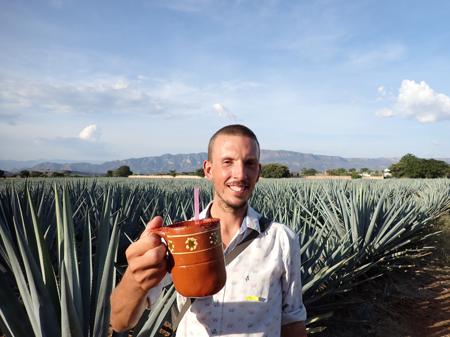Rob in a field of agave showing his "cantarito" made of clay painted in the traditional Mexican way
