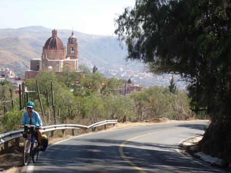 Ruth trying hard to pedal up the hill with views down into the valley and a church in the background