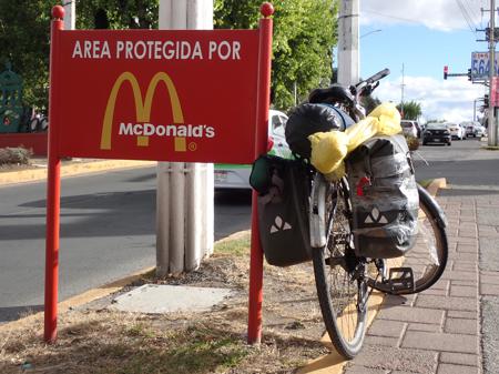 Ruth's bike leaning against a sign saying 'area protected by McDonald's'