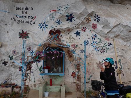 Ruth praying by a virgin on the side of a mountain, the cliff face is painted in colourful flowers