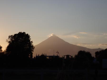 An active volcano as seen from Cholula, a cloud hangs around the summit