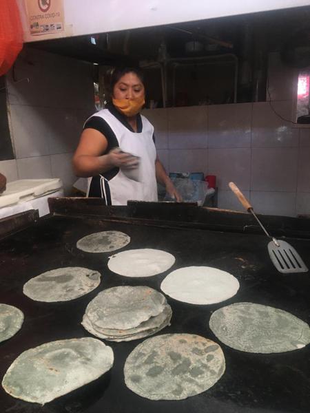A woman with various blue tortillas toasting away