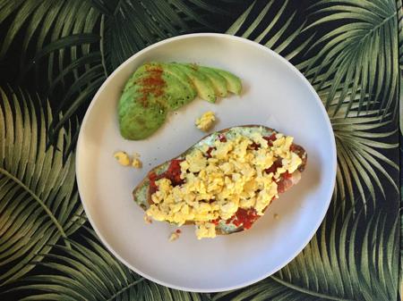 Scrambled egg, Spanish ham, red peppers and pesto on toast with avocado and a tropical background