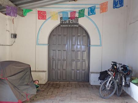 Camping where pilgrims stay behind the church in the town of Valdeflores, the bikes are leaning to one side of a door and the tent is pitched to the other