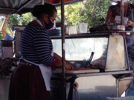 Woman cooking tacos at a very busy street food stand